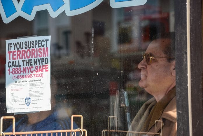 A man looks out a window near an address associated with suspected terrorist Akayed Ullah