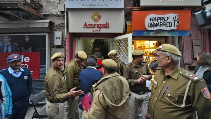 Police personnel outside shops in the Khan Market, in New Delhi on Monday.