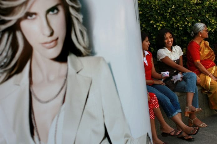 Women sit outside a shopping centre, in Bangalore, India