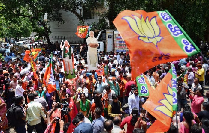 BJP workers celebrate the party's lead in more than 100 assembly seats, outside the party office in Bengaluru Tuesday