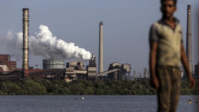 A laborer walks near the JSW Steel Ltd. manufacturing facility in Dolvi, Maharashtra. Photographer: Dhiraj Singh/Bloomberg
