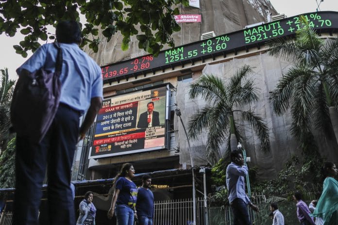 A man looks up at an electronic ticker board that indicates stock figures at the Bombay Stock Exchange (BSE)