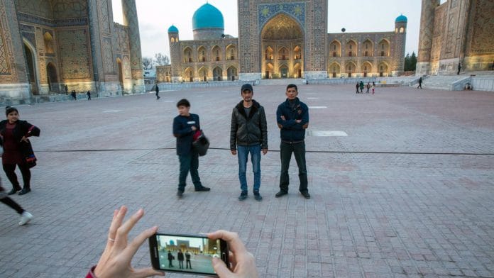 Visitors pose for a photograph at Registan Square in Samarkand, Uzbekistan | Taylor Weidman/Bloomberg