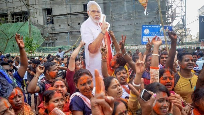 BJP supporters hold up a placard of PM Narendra Modi in in Agartala| PTI