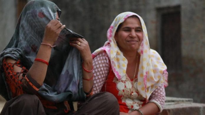 Garvesh (left) covers her face as a man passes by