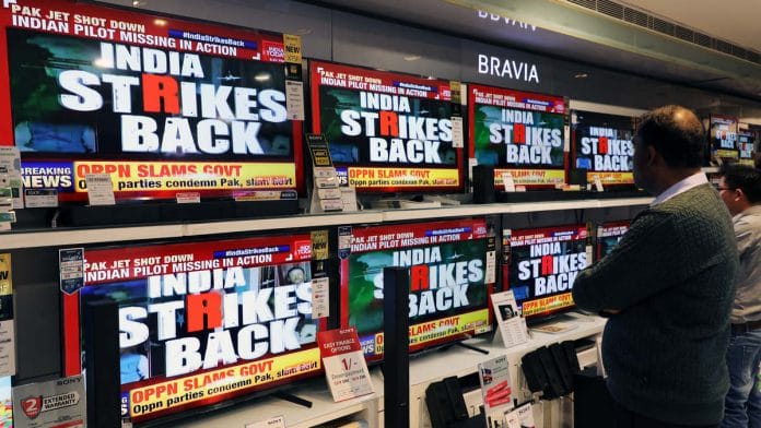 A man watches a television news report on the confrontation between Indian and Pakistani fighter jets in an electronics store in New Delhi
