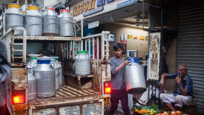 A worker loads a truck with milk cans