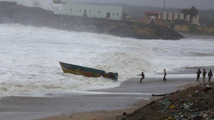 Fishermen try to control their boat amidst rough sea waters at Veraval, in Gir Somnath