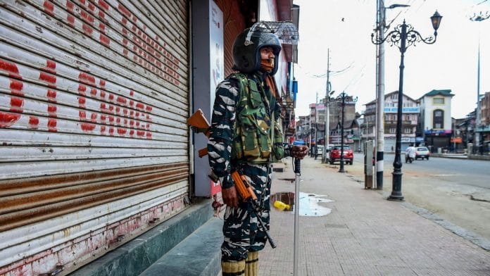 A security personnel stands guard outside closed shops, in Srinagar