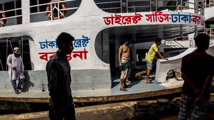 Men stand on a ship docked at the Sadarghat boat terminal in Dhaka, Bangladesh | Photographer: Ismail Ferdous | Bloomberg