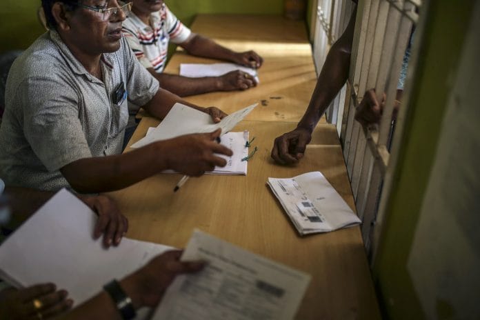 Officials check for a man's name on the National Register of Citizens at a government office in Guwahati, Assam on 31 August. | Photo: Dhiraj Singh/Bloomberg