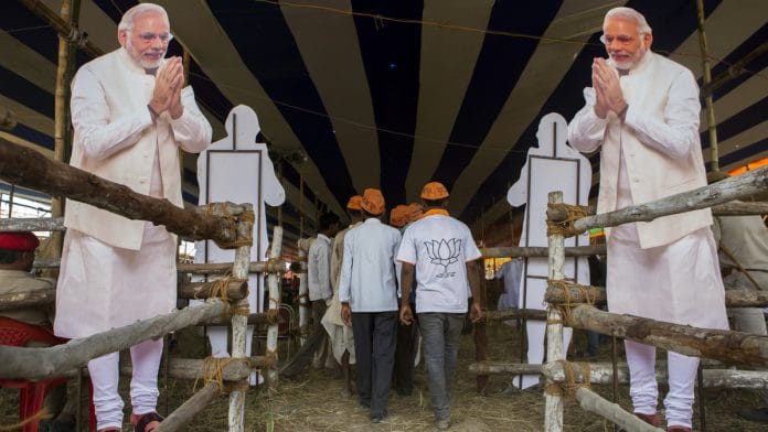 File photo | BJP supporters walk past paper cut outs of PM Modi during a rally in Muzaffarpur, Bihar | Prashanth Vishwanathan/Bloomberg