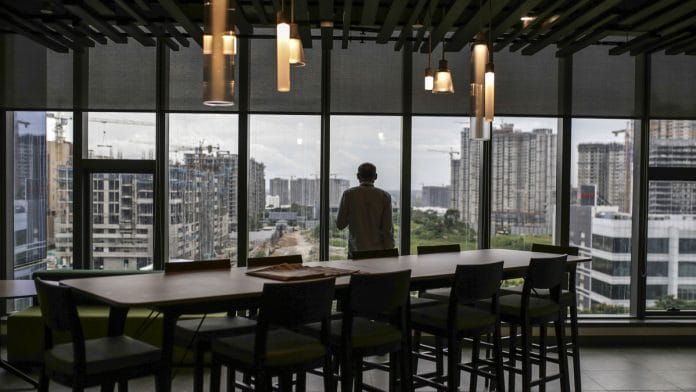 An employee standing at the window looks out over construction sites from the Amazon.com Inc. office campus in Hyderabad