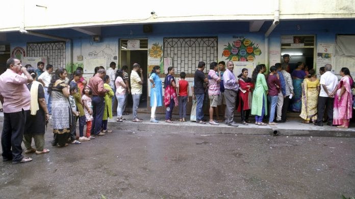 Voters stand in a queue outside a polling station during Maharashtra Assembly elections, in Thane.