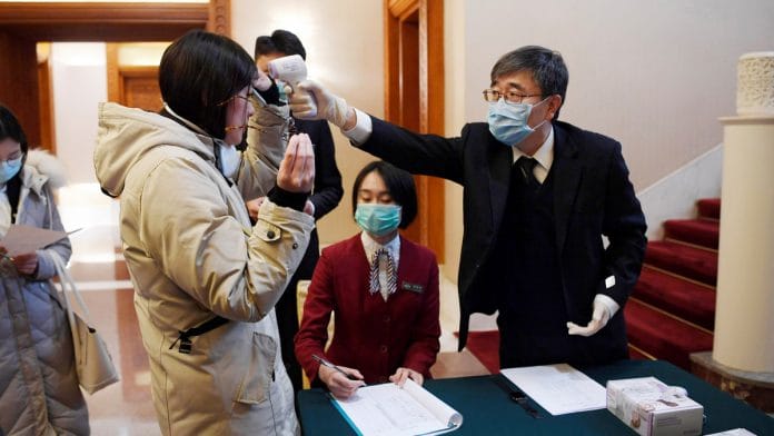 A man uses a thermometer to check the temperature of a journalist covering a meeting between Tedros Adhanom, director-general of the World Health Organization, and Chinese Foreign Minister Wang Yi in Beijing on Tuesday | ANI/Reuters