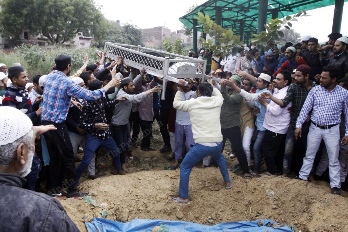 After completing the journey of over a kilometer, many lend their hand to lay the bodies to rest inside the cemetery in Mustafabad | Photo: Praveen Jain | ThePrint