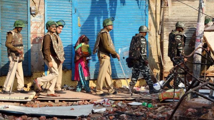Delhi Police personnel walk through rubble in Bhajanpura area Thursday, the fifth day since violence broke out in the northeast district, resulting in more than 30 deaths | Suraj Singh Bisht | ThePrint