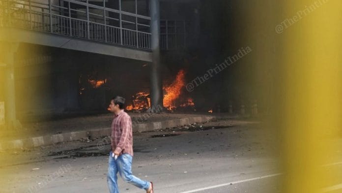 A man walks by a fire burning at a walkway in Northeast Delhi's Gokulpuri on 25 February 2020 | Manisha Mondal | ThePrint