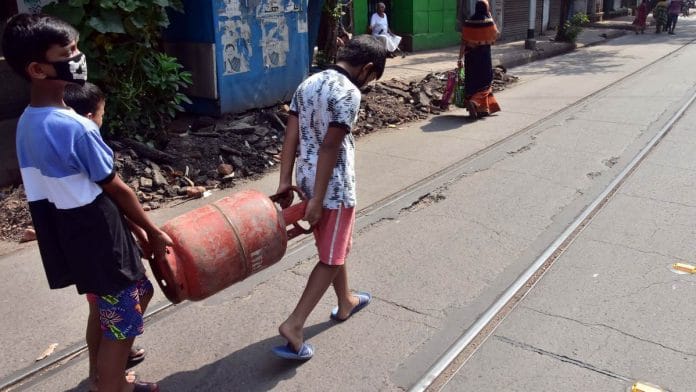 Two children wearing masks carry a gas cylinder amid the coronavirus outbreak in India | Photo: ANI