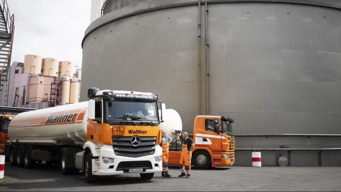 Oil tanker trucks sit parked beside storage silos at the Erik Walther GmbH oil terminal on the River Rhine in Schweinfurt, Germany. | Photographer: Alex Kraus | Bloomberg