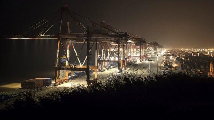 Gantry cranes operate as containers sit stacked at the Yangshan Deepwater Port in Shanghai. | Bloomberg