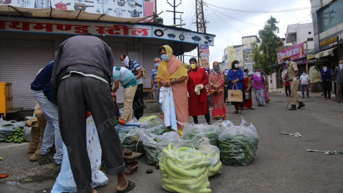Residents of Bhilwara queue up to buy vegetables as a policeman (right) ensures social distancing on 27 March | Photo: Manisha Mondal | ThePrint