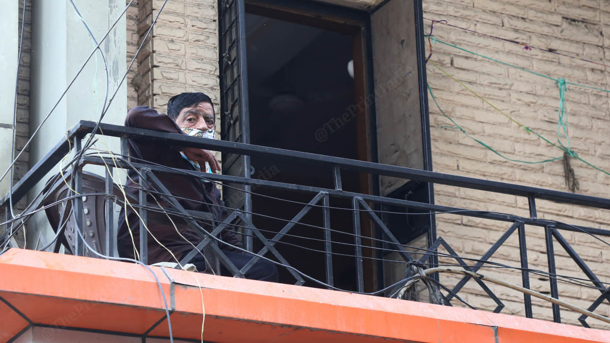 A resident sits on his balcony in Tughlaqabad Extension | Photo: Manisha Mondal | ThePrint