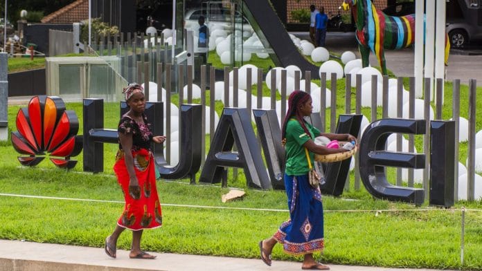 Pedestrians pass by a company logo outside the Huawei Technologies Co. offices in Lusaka, Zambia. | Bloomberg