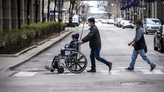 A man pushes a wheelchair towards Northwestern Memorial Hospital in Chicago, Illinois, U.S. | Photographer: Christopher Dilts | Bloomberg