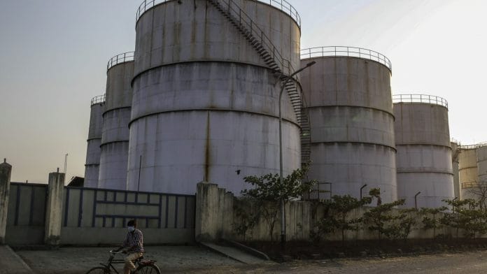 A cyclist rides past oil storage tanks at Jawaharlal Nehru Port, operated by Jawaharlal Nehru Port Trust (JNPT), in Navi Mumbai, Maharashtra | Photographer: Dhiraj Singh | Bloomberg