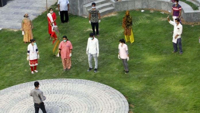 People who recovered from Covid-19 stand for a group photograph, albeit with social distancing, in the lawn of the quarantine centre at Vadodara | Praveen Jain | ThePrint