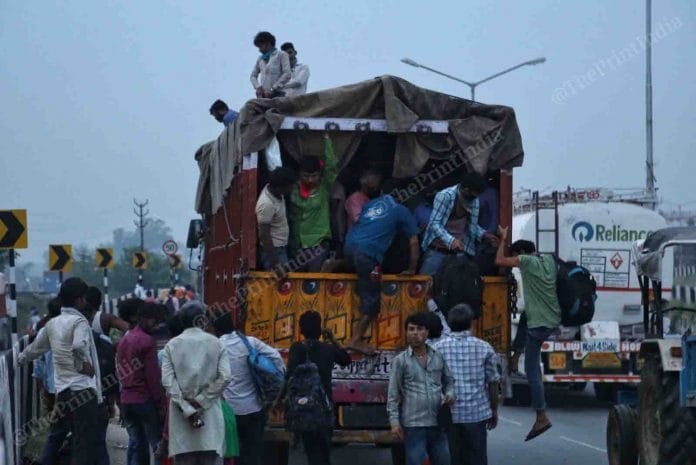 The workers look for some lift services ,trying to stop running trucks that will take them their to hometown | Photo: Suraj Singh Bisht | ThePrint
