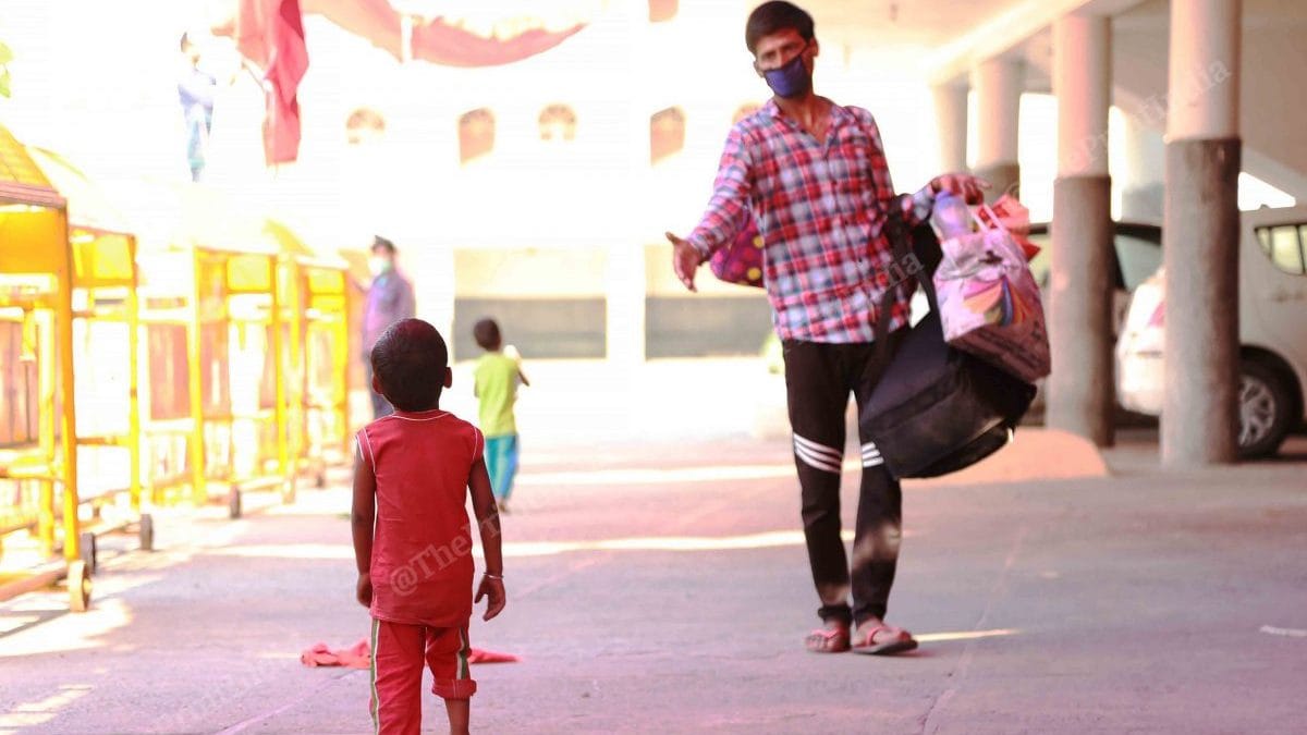 A father extends his hand to her daughter before the last process to board the bus that will take them to their homes in Bhagalpur | Manisha Mondal | ThePrint