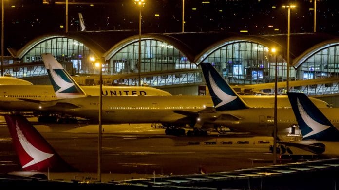 Tail fins of Cathay Dragon, left, and Cathay Pacific Airways Ltd. aircraft are seen at Hong Kong International Airport at night in Hong Kong, China | Photographer: Paul Yeung | Bloomberg
