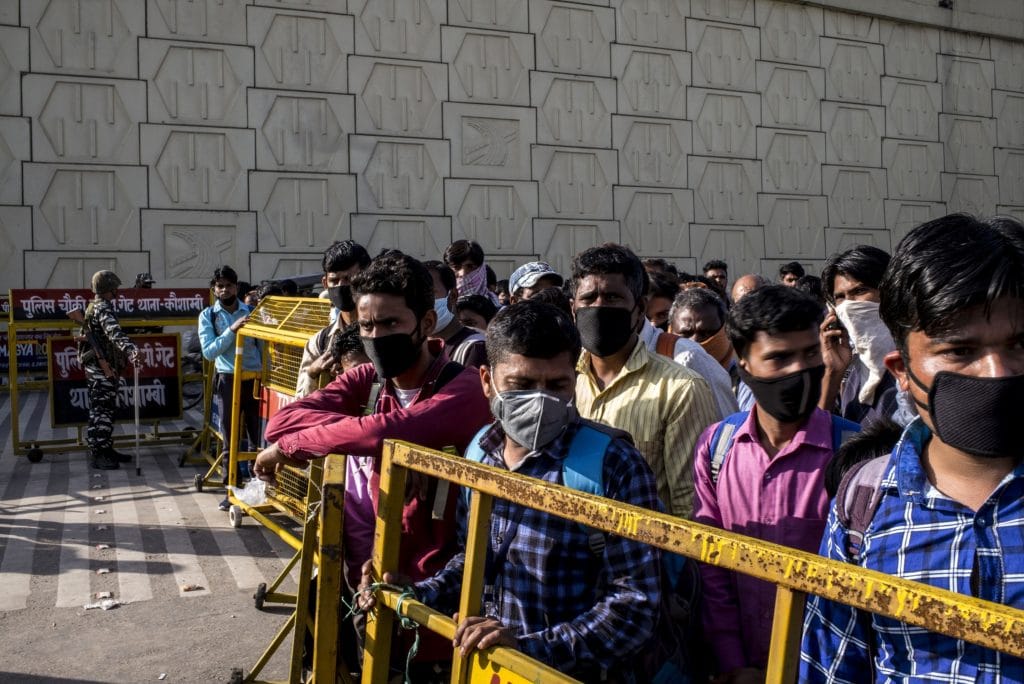 Migrant workers and their families are held behind a barrier at a police checkpoint in New Delhi, on March 28. | Photo: Anindito Mukherjee | Bloomberg