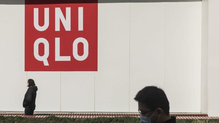 Pedestrians wearing protective masks walk past a Uniqlo store, operated by Fast Retailing Co., on Nanjing Road in Shanghai, China.| Photographer: Qilai Shen | Bloomberg