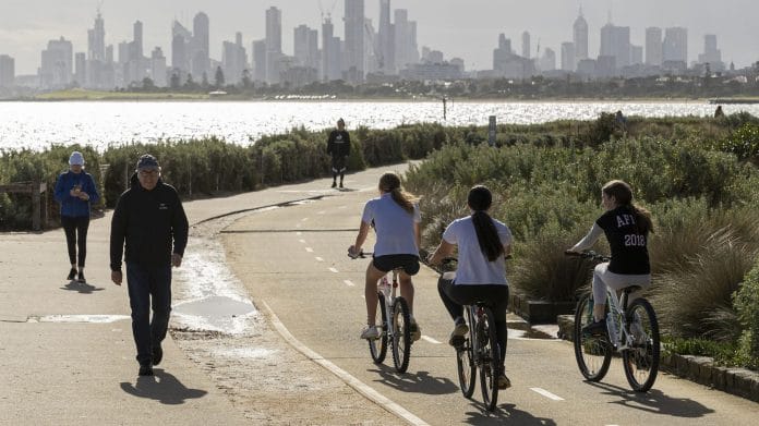 People walk and ride along the beach at Brighton on May 13, 2020 in Melbourne, Australia. COVID-19 restrictions have eased slightly for Victorians in response to Australia's declining coronavirus infection rate. | Photo by Daniel Pockett | Getty Images | Bloomberg