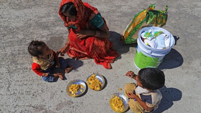 A migrant worker that was unable to catch a bus feeds her children on the side of National Highway 24 during Covid lockdown in Delhi