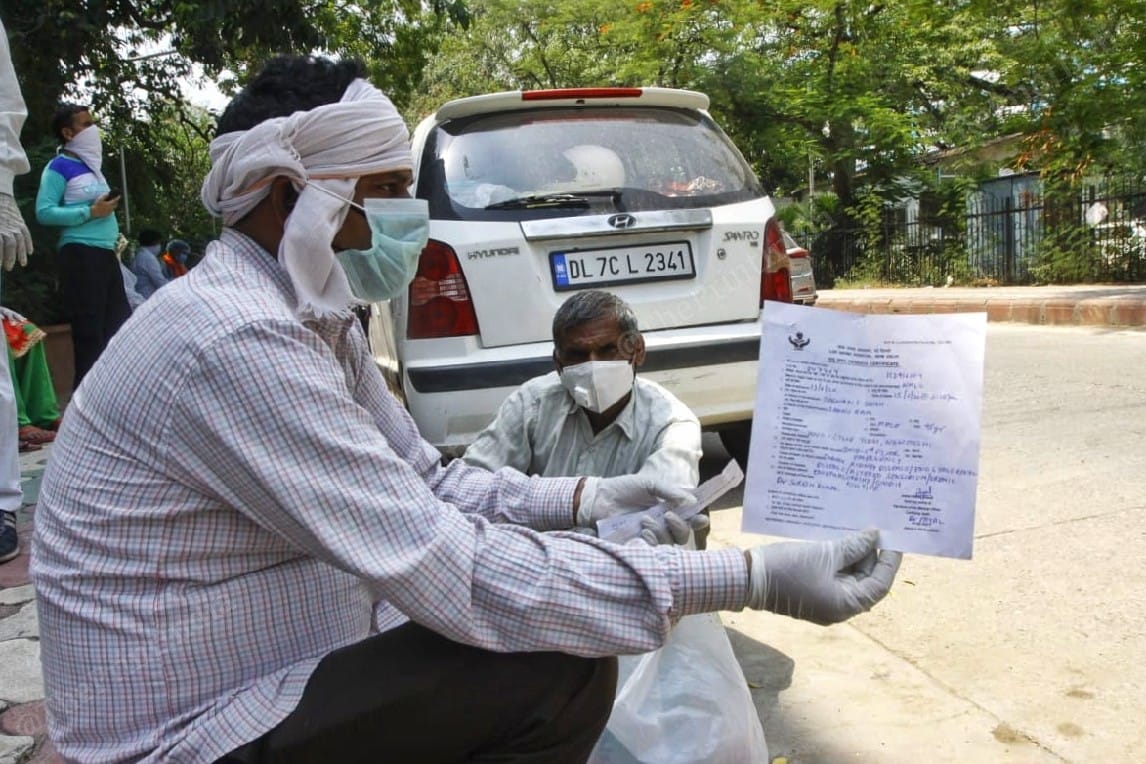 Rakesh Kumar holds up the death certificate for his father | Praveen Jain | ThePrint