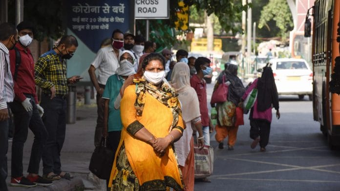 Passengers wait for a DTC bus to reach their destination at a bus stop, during the ongoing COVID-19 lockdown, in New Delhi | PTI