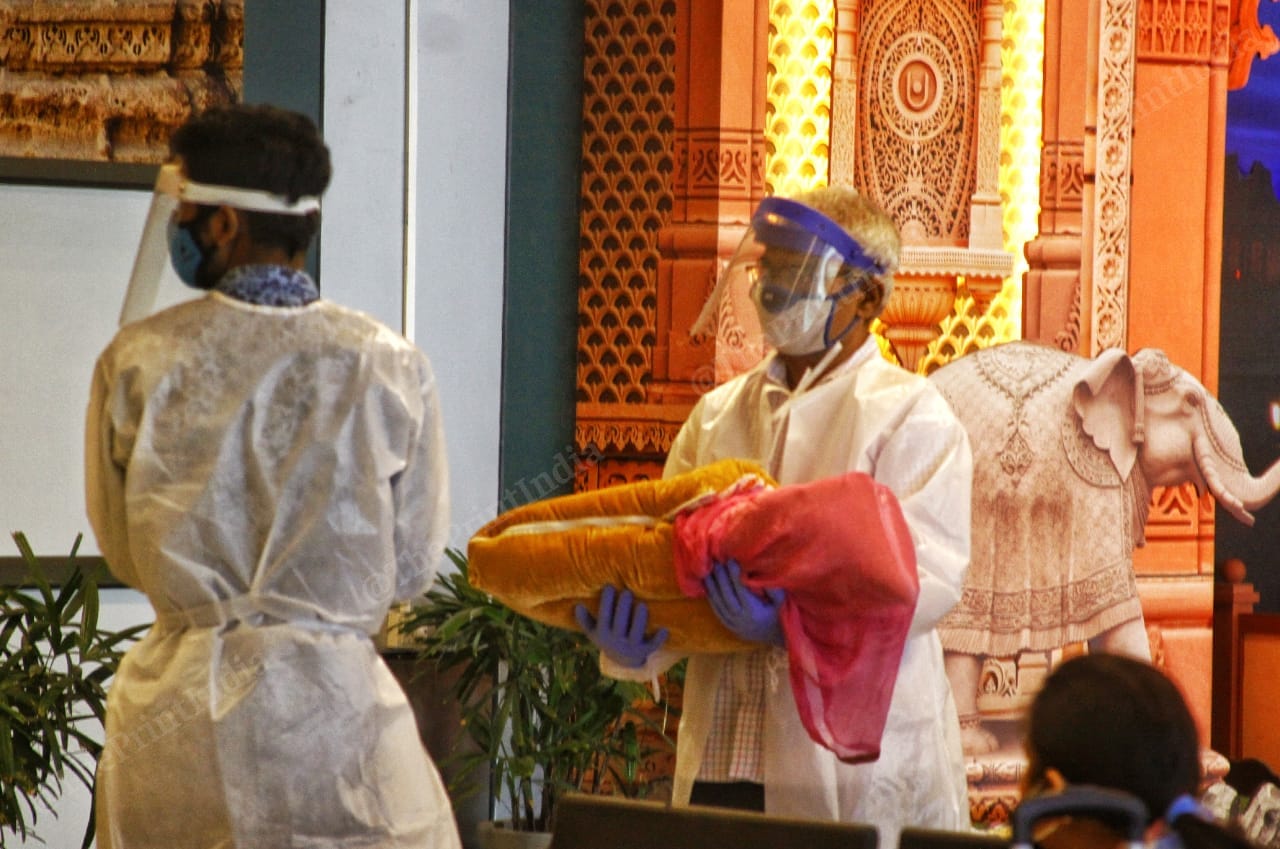 A man in protective gear holds his child, whom he has bundled up into a blanket as protection against the virus | Praveen Jain | ThePrint