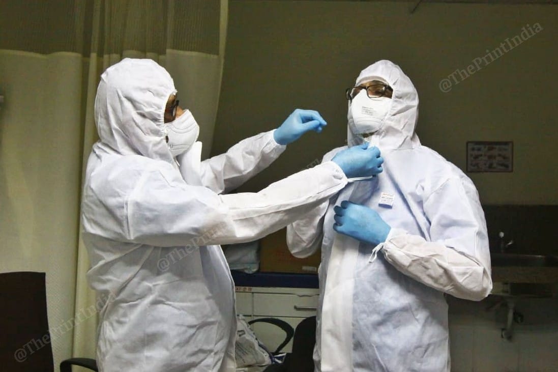 Dr Rakesh Joshi (left), Additional Medical Superintendent, Ahmedabad Civil Hospital, helps Dr Rajnish Patel, Additional Medical Superintendent, Ahmedabad Civil Hospital, with his PPE kit | Photo: Praveen Jain | ThePrint
