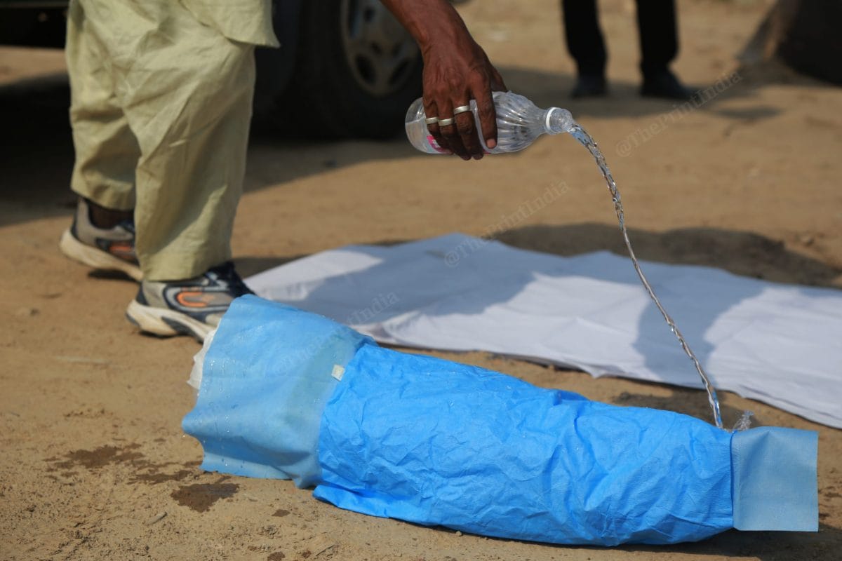 Caretaker of the graveyard Shamim gives water to the infant for the last time | Photo: Manisha Mondal | ThePrint