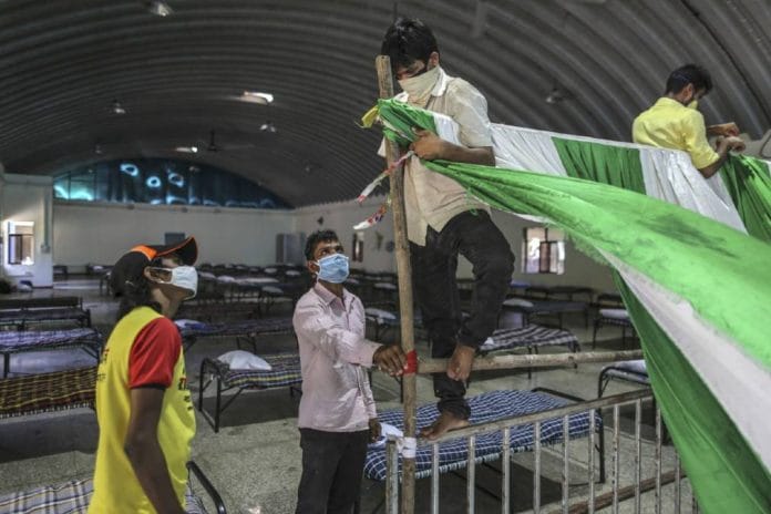 Workers install a cloth partition at the Covid-19 hospital in the Nehru Science Centre in Mumbai | Bloomberg