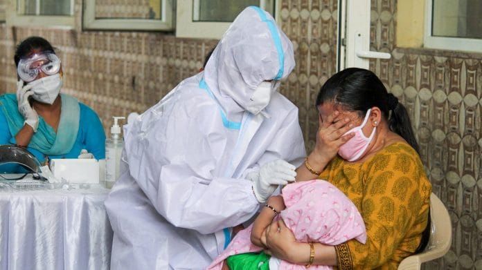 A mother reacts as a medic attempts to collect samples from her infant child for COVID-19 rapid antigen testing, in Gurugram | PTI
