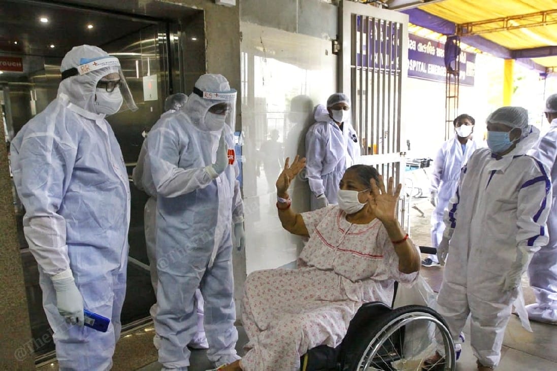 A woman waves goodbye to her doctors while getting discharged from the hospital after her recovery from Covid-19 | Photo: Praveen Jain | ThePrint