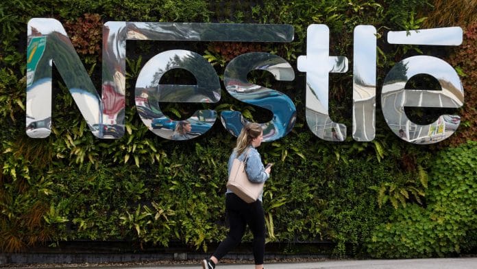 A pedestrian passes a Nestle SA logo at the Nescafe factory, operated by Nestle SA, in Tutbury, UK | Photographer: Simon Dawson | Bloomberg