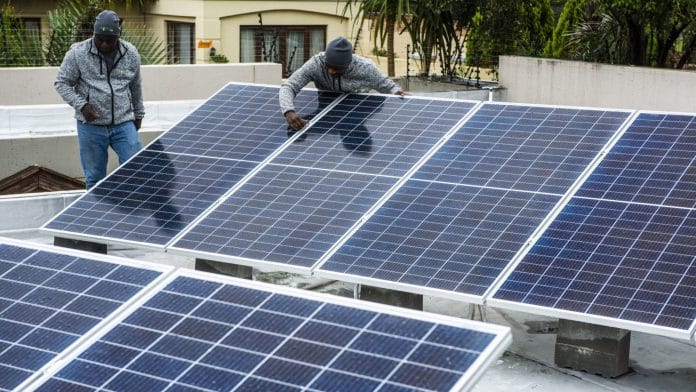 Workers install solar panels onto the roof of a residential property in Johannesburg | Waldo Swiegers | Bloomberg