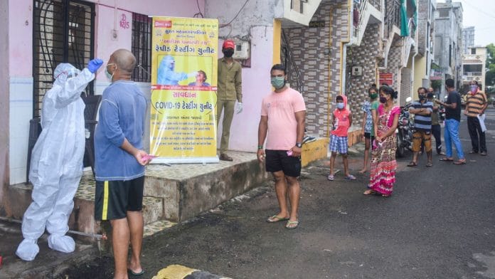 A medic collects a sample from a man for a Covid-19 test as others wait for their turn, in Surat, on 6 August 2020 | PTI