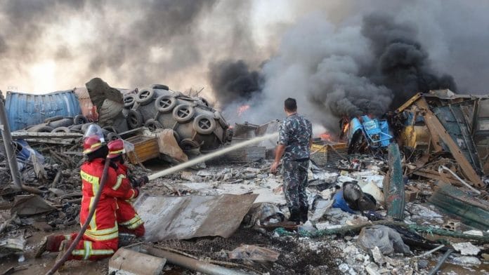 Firefighters extinguish flames at nearby damaged buildings following a large explosion at the Port of Beirut | Bloomberg